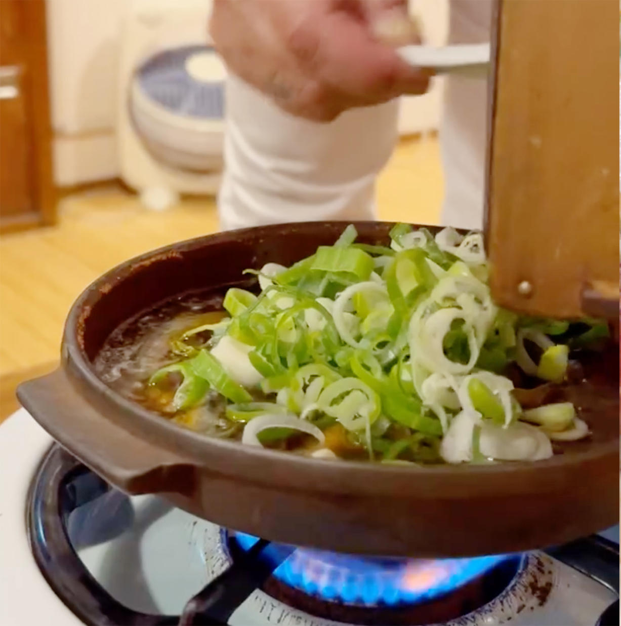 どじょう（どぜう）鍋にネギを入れている場面